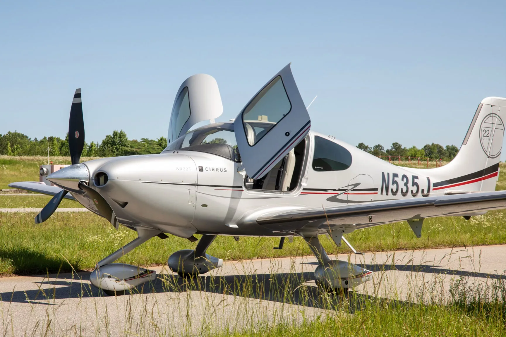 A silver Cirrus SR22T aircraft with registration N535J is parked with both doors open, viewed from the front-quarter angle.