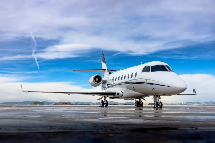 Front view of a white Gulfstream G280 on the tarmac with a blue stripe.