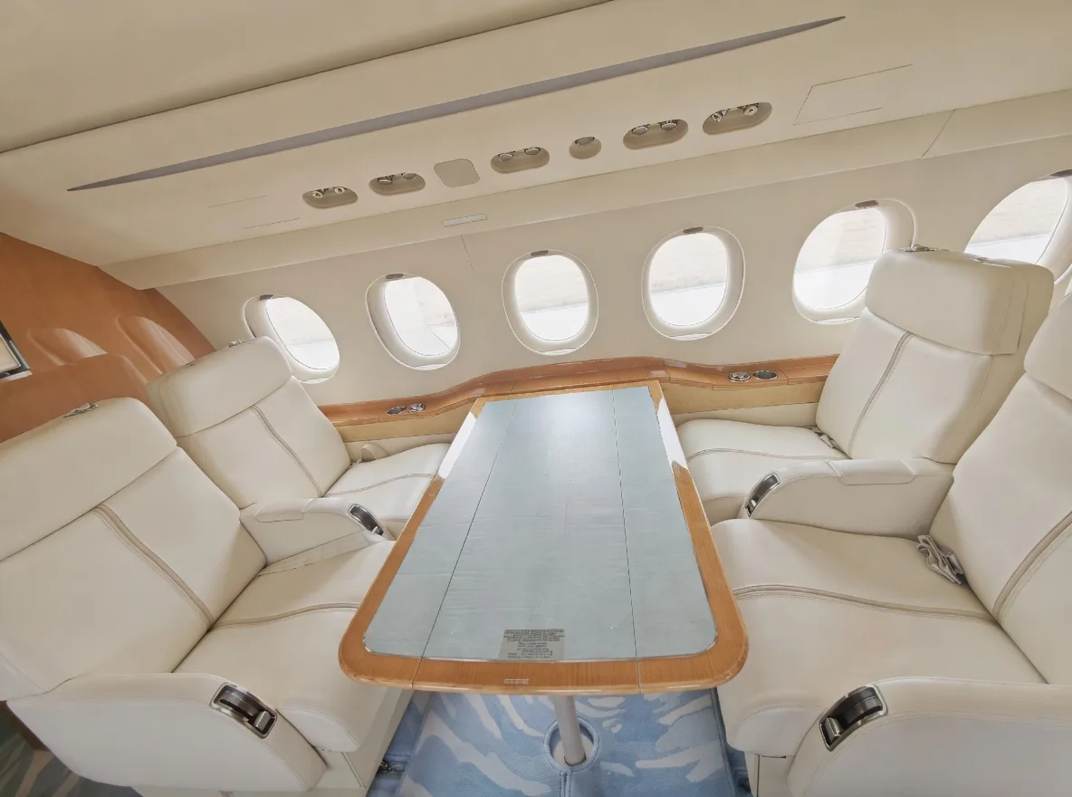 A close-up of a large rectangular dining table surrounded by cream leather seats in an aircraft cabin.
