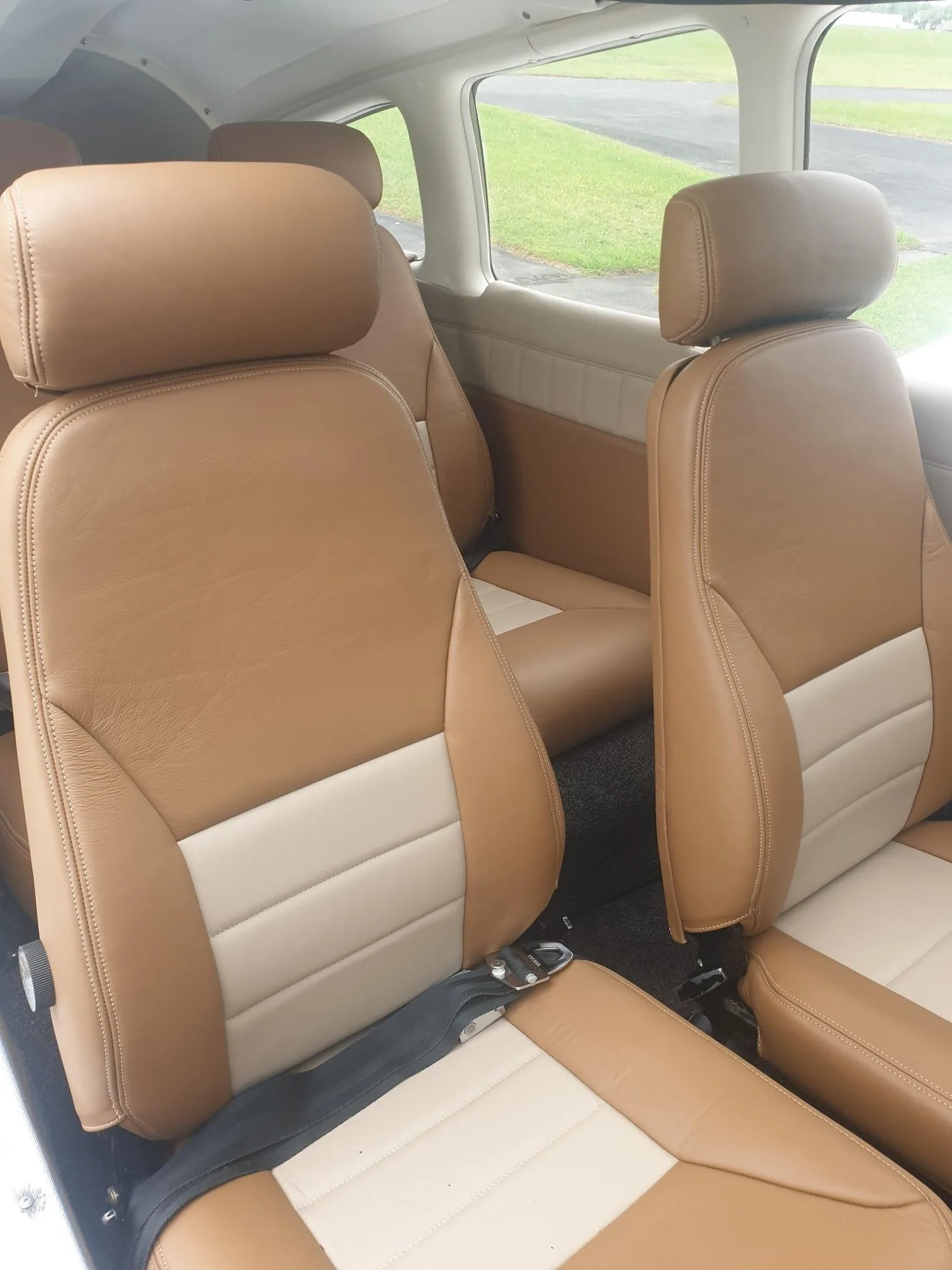 The interior cabin of an aircraft showing tan and cream leather seats.