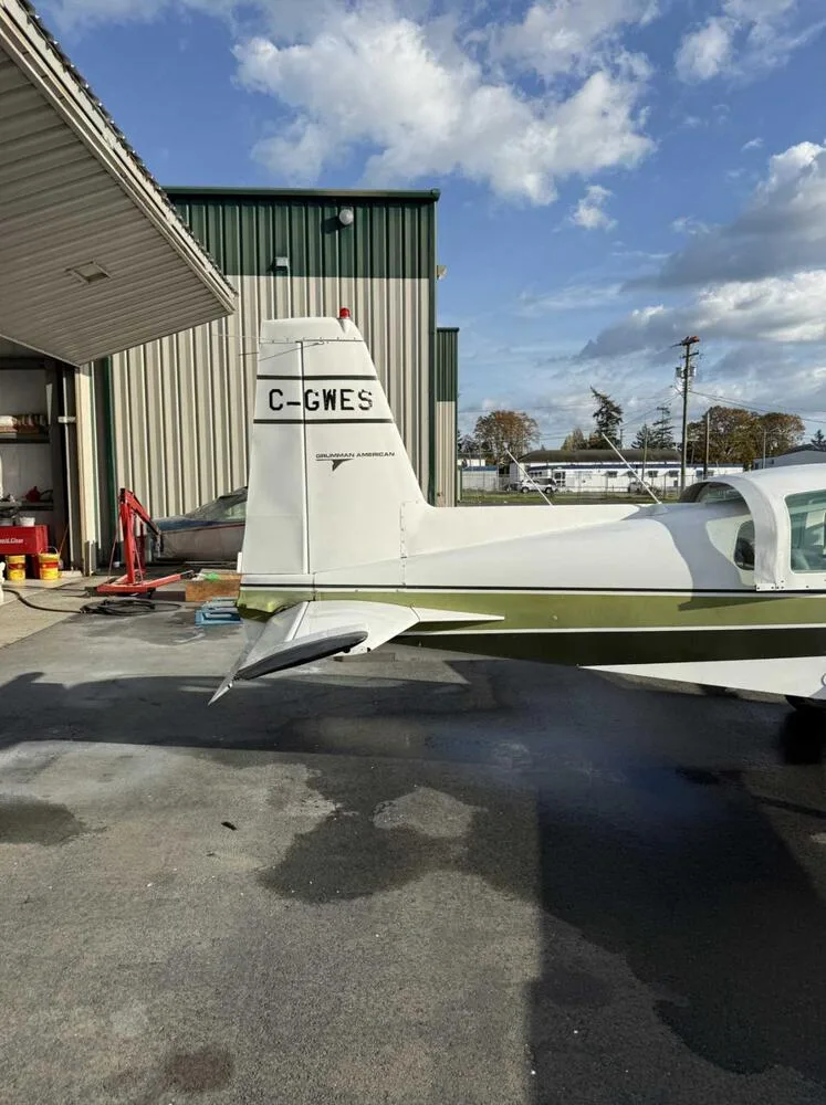 Rear view of the tail of a white Grumman American AA-5 Traveler aircraft showing the C-GWES registration and logo.