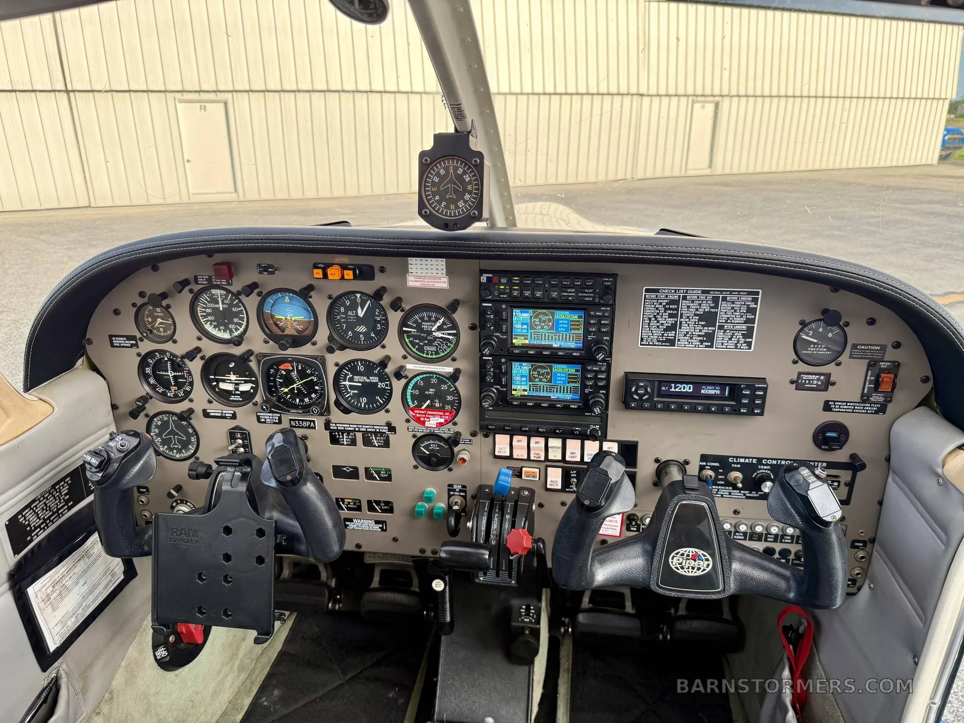 The cockpit of a Piper Cherokee aircraft, showing the instrument panel with avionics, gauges, and yokes.