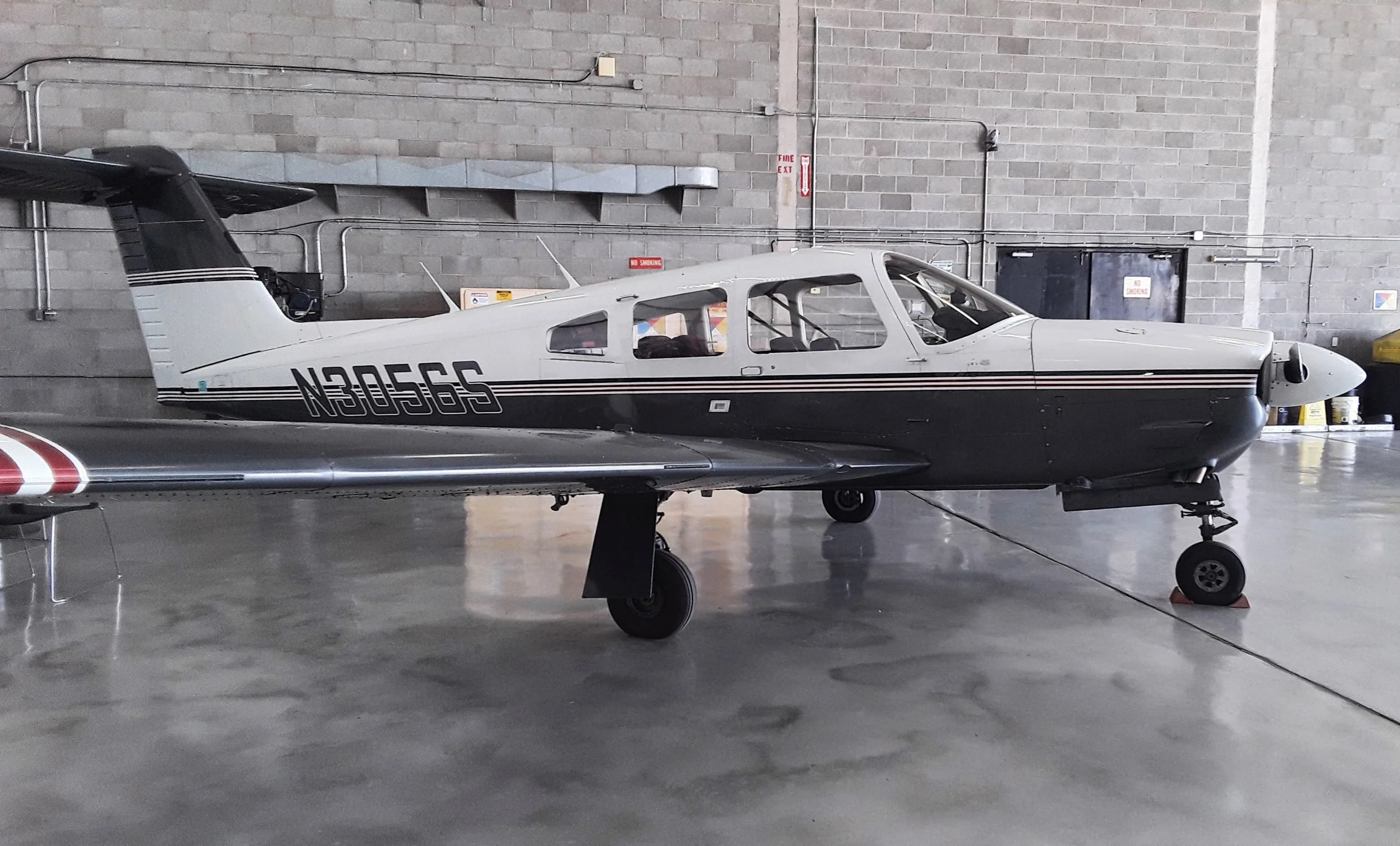 A white and dark grey single-engine propeller aircraft with registration N305GS parked in a hangar.