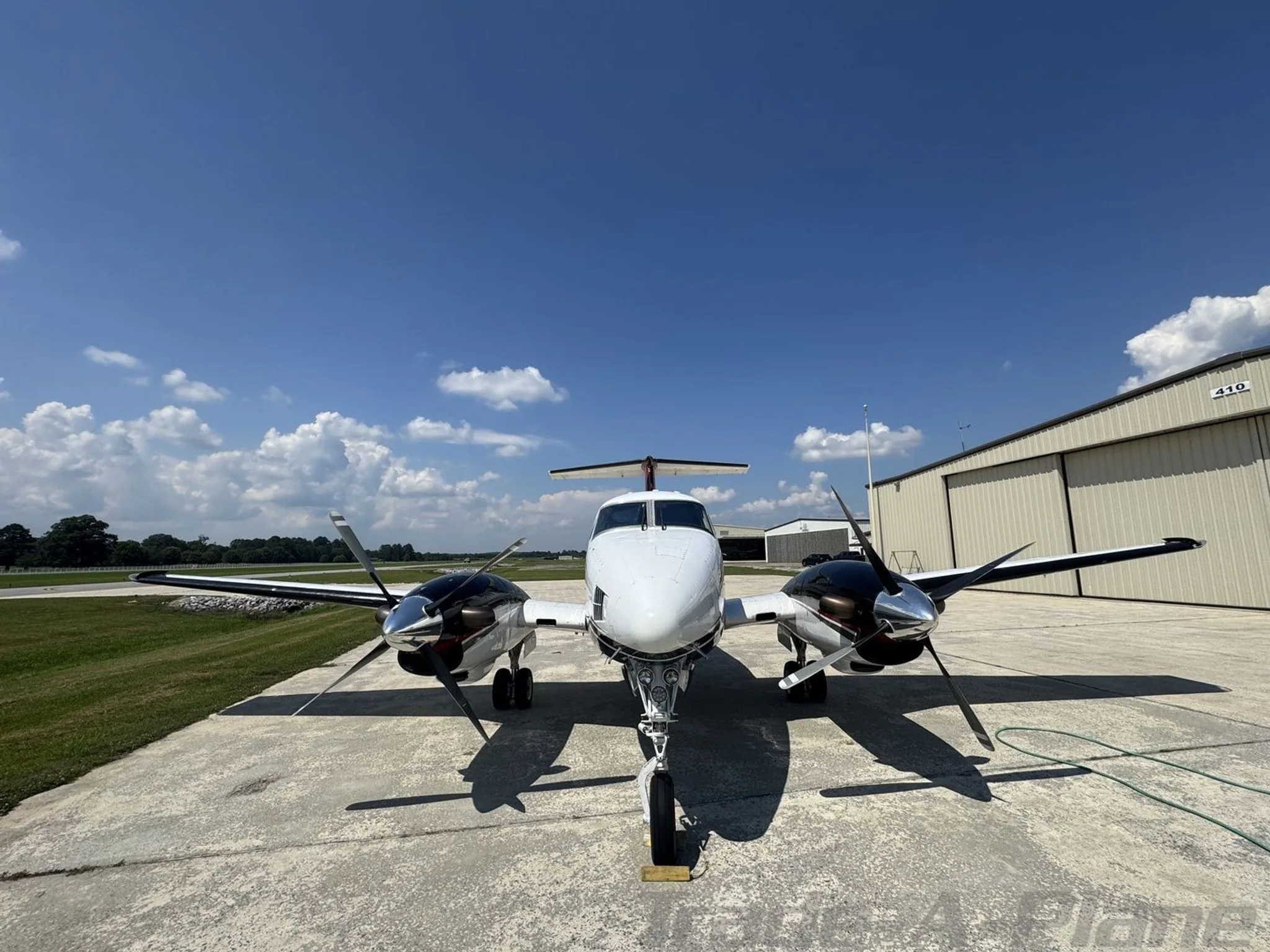 A head-on view of a white and black Beechcraft King Air F90, N490TX, parked on a concrete surface with its propellers visible.