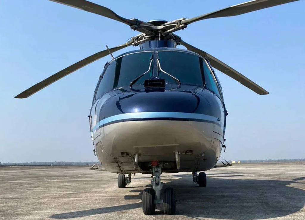 A head-on view of a dark blue and silver Airbus H155 helicopter parked on an airfield.