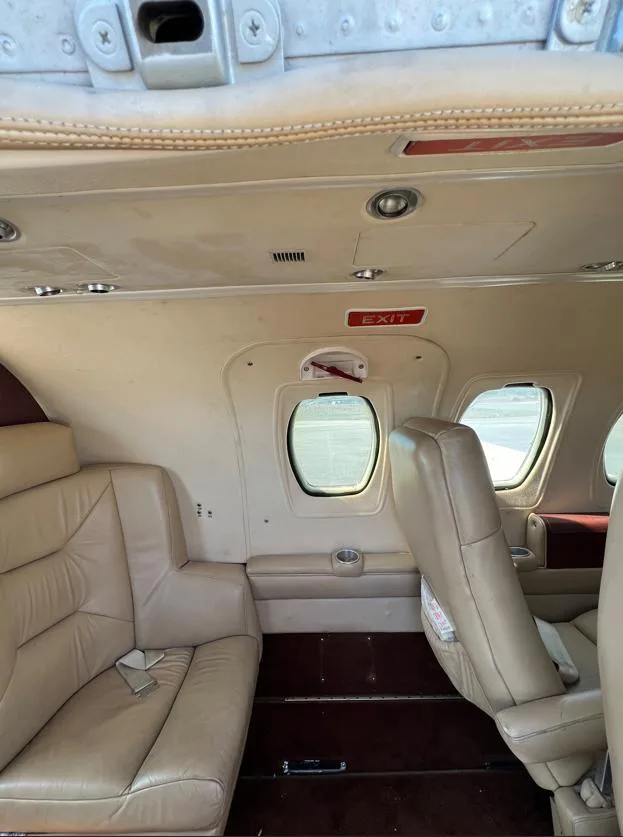 The interior cabin of a business jet, featuring tan leather seats and windows.