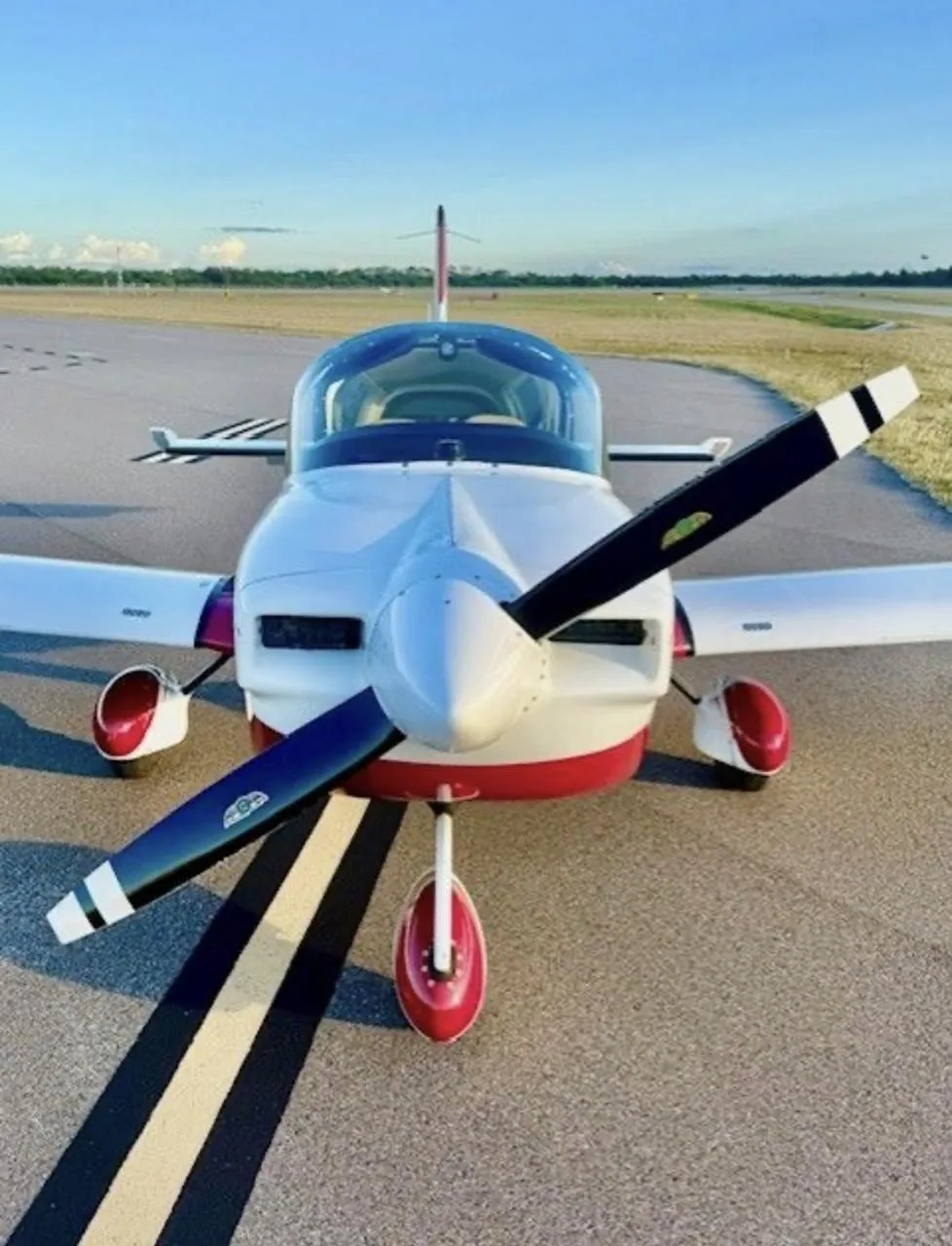 A head-on view of a white and red American General AG-5B Tiger aircraft with registration N133U on a runway.