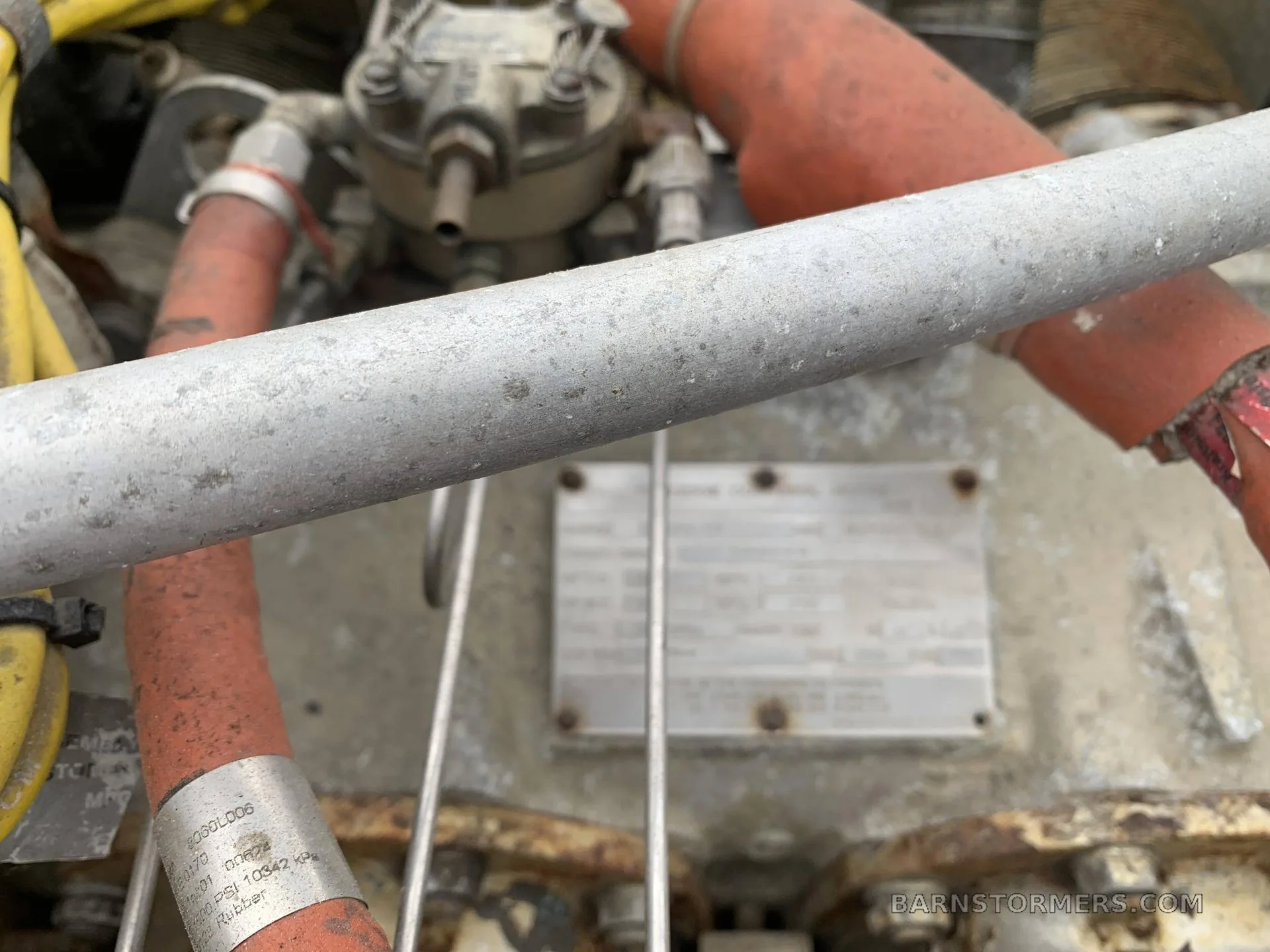 An extreme close-up of an aircraft engine's components, including a data plate and red hoses.