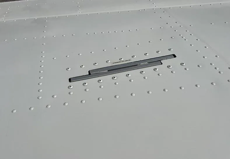 Close-up view of a riveted aircraft surface with a vent or access panel.