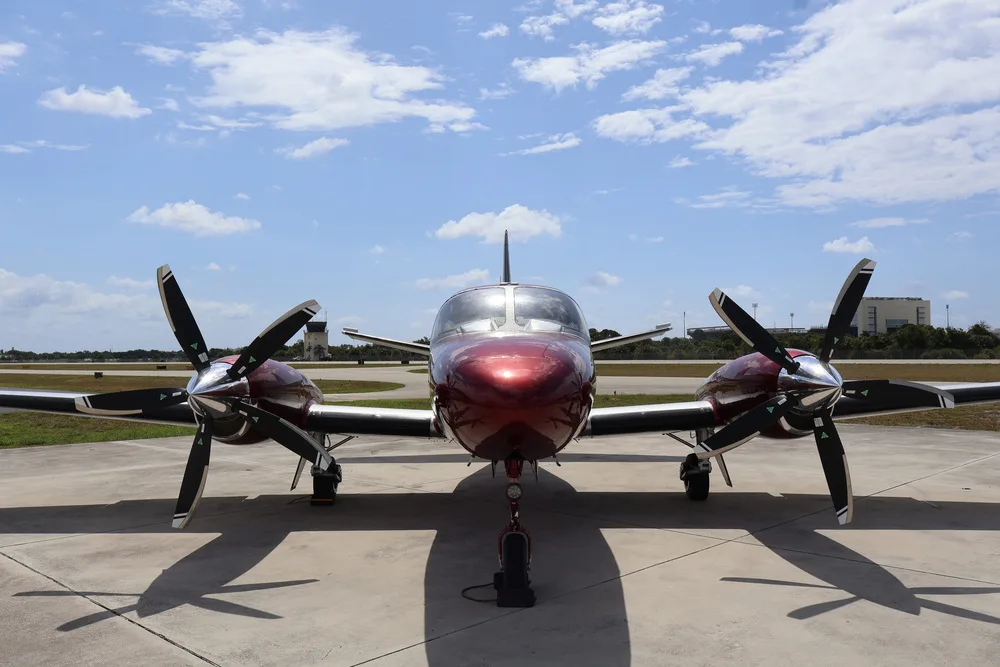 A head-on view of the red and silver twin-engine aircraft N441JT with its propellers prominently displayed.