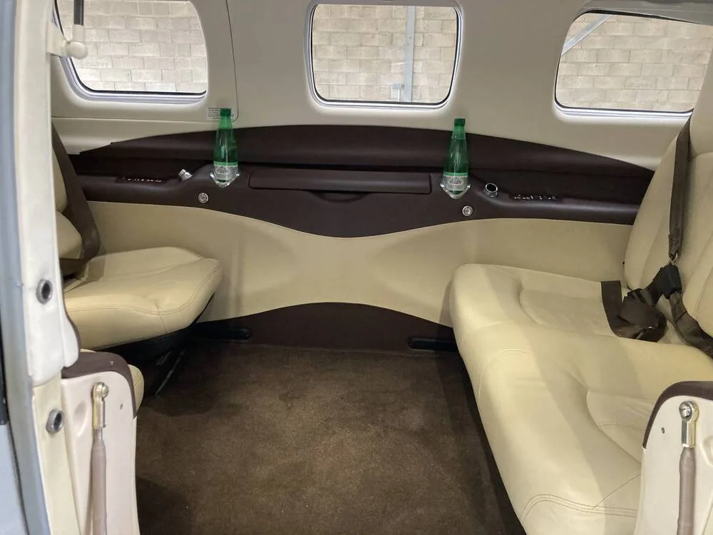 The beige and brown interior cabin of the aircraft, showing two rows of passenger seats and water bottles.
