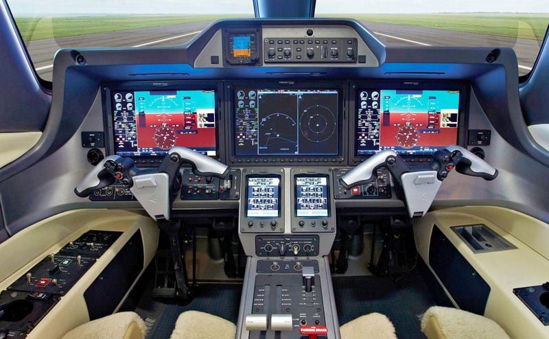 Detailed view of an aircraft cockpit with multiple display screens and controls.
