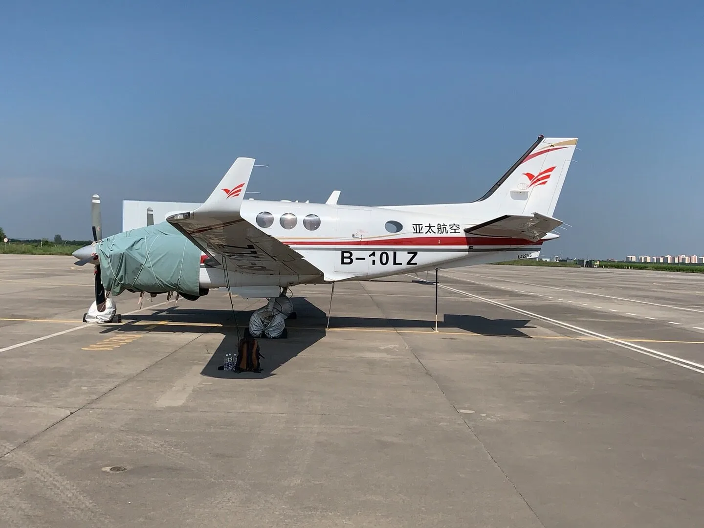 A King Air B-10LZ aircraft is parked on the tarmac with propeller covers.