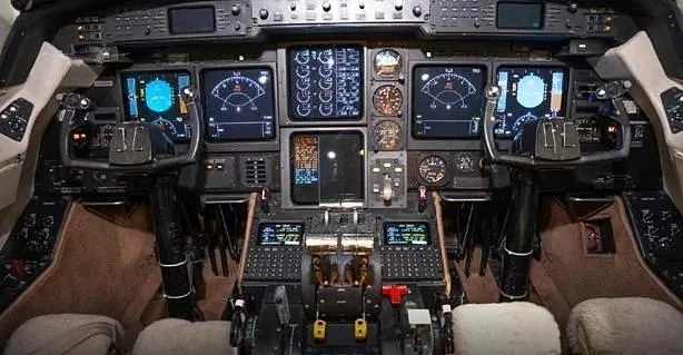 The cockpit of a business jet features a complex array of digital displays, gauges, and control panels.