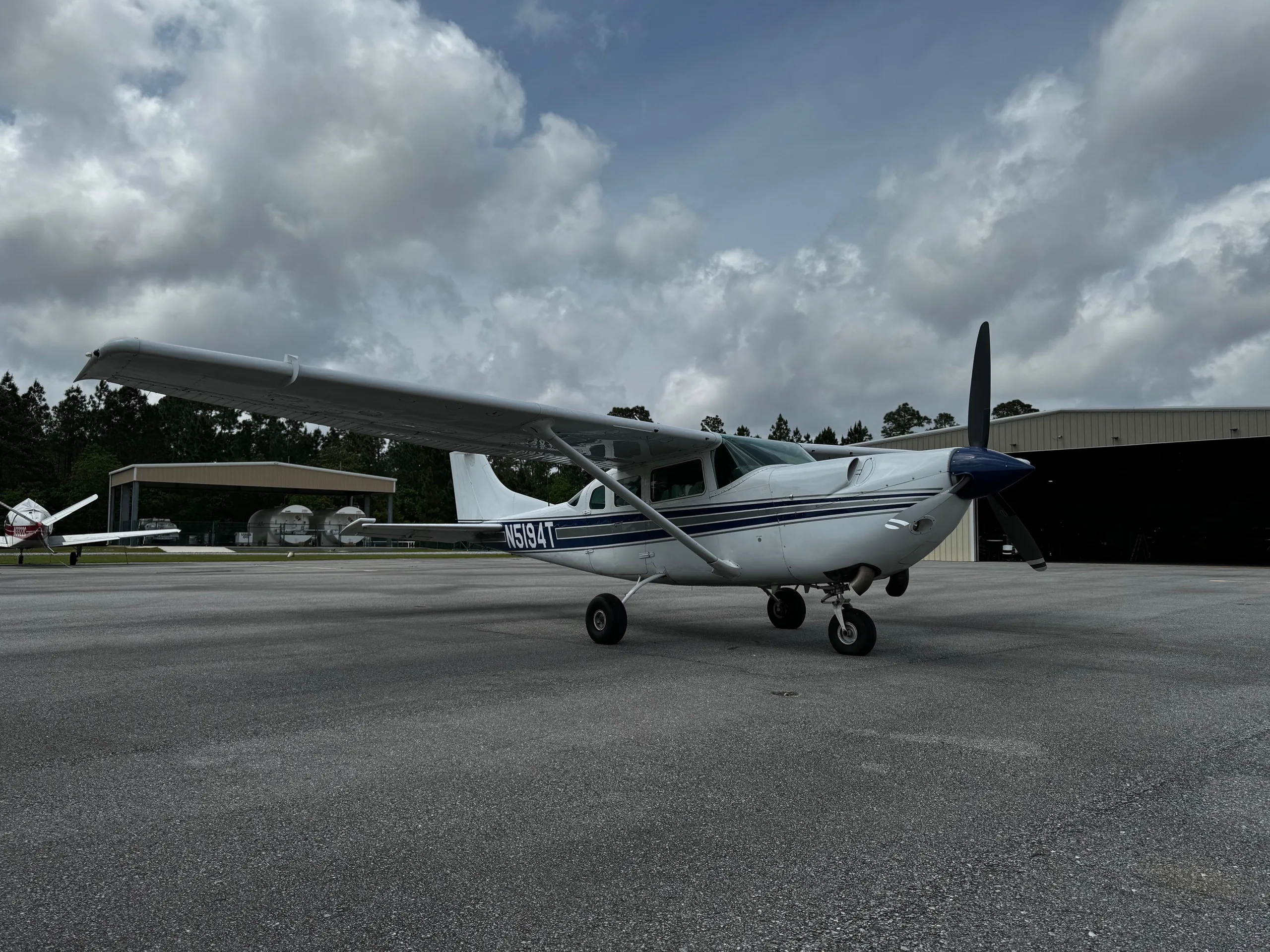 Side view of a white and blue Cessna 206 Turbo Stationair with tail number N5194T on the tarmac.