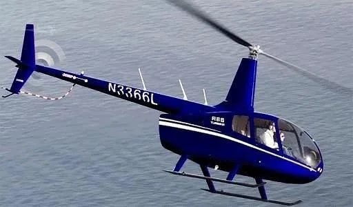 A blue Robinson R66 Turbo helicopter with registration N3366L flying over water.
