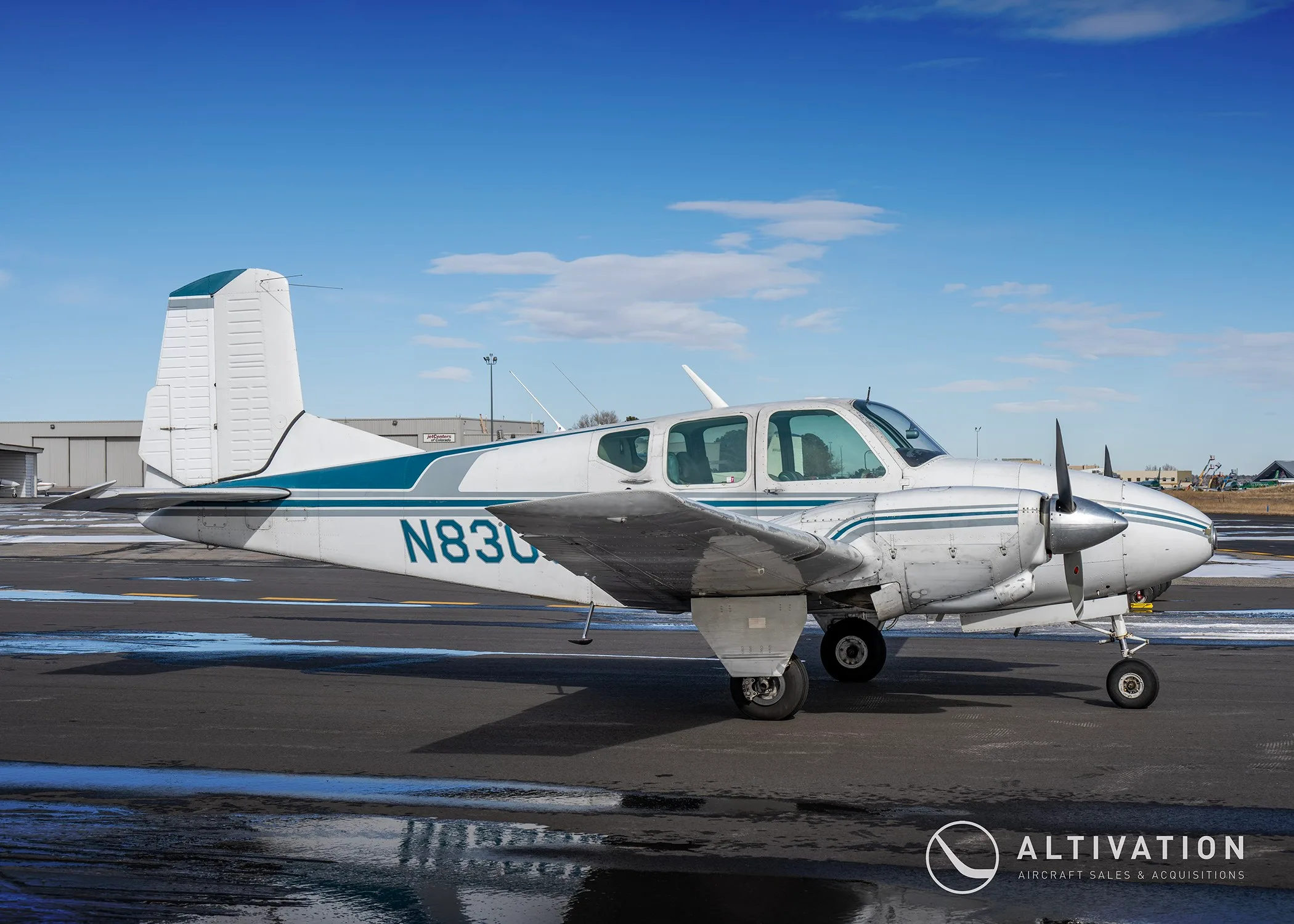 Left side view of a white and blue twin-engine propeller aircraft with registration N830 visible on the fuselage.