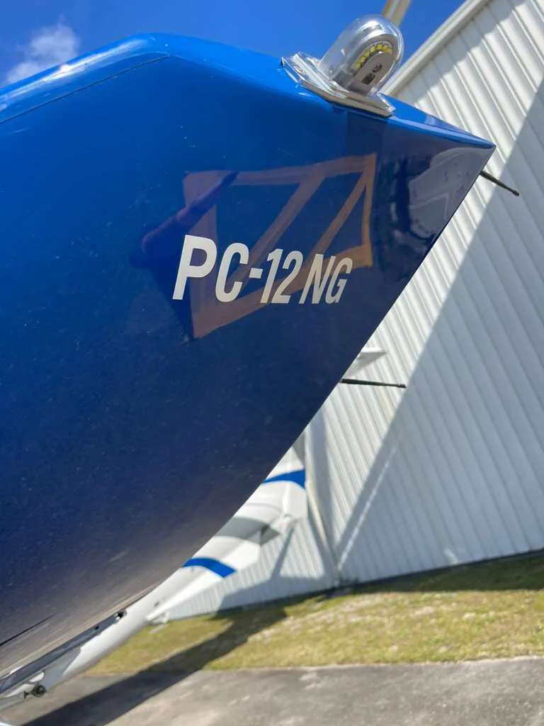 A close-up view of the blue tail section of a Pilatus PC-12 NG aircraft, showing "PC-12 NG" in white text.