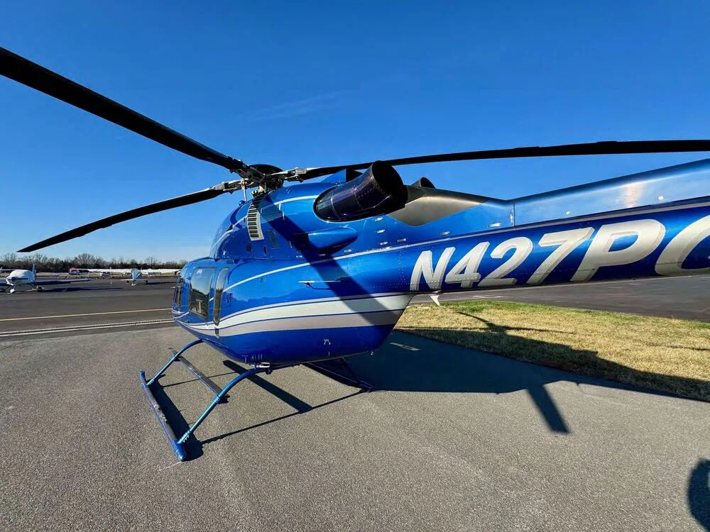 A close-up side view of the blue Bell 427 helicopter fuselage showing the N427PG registration.