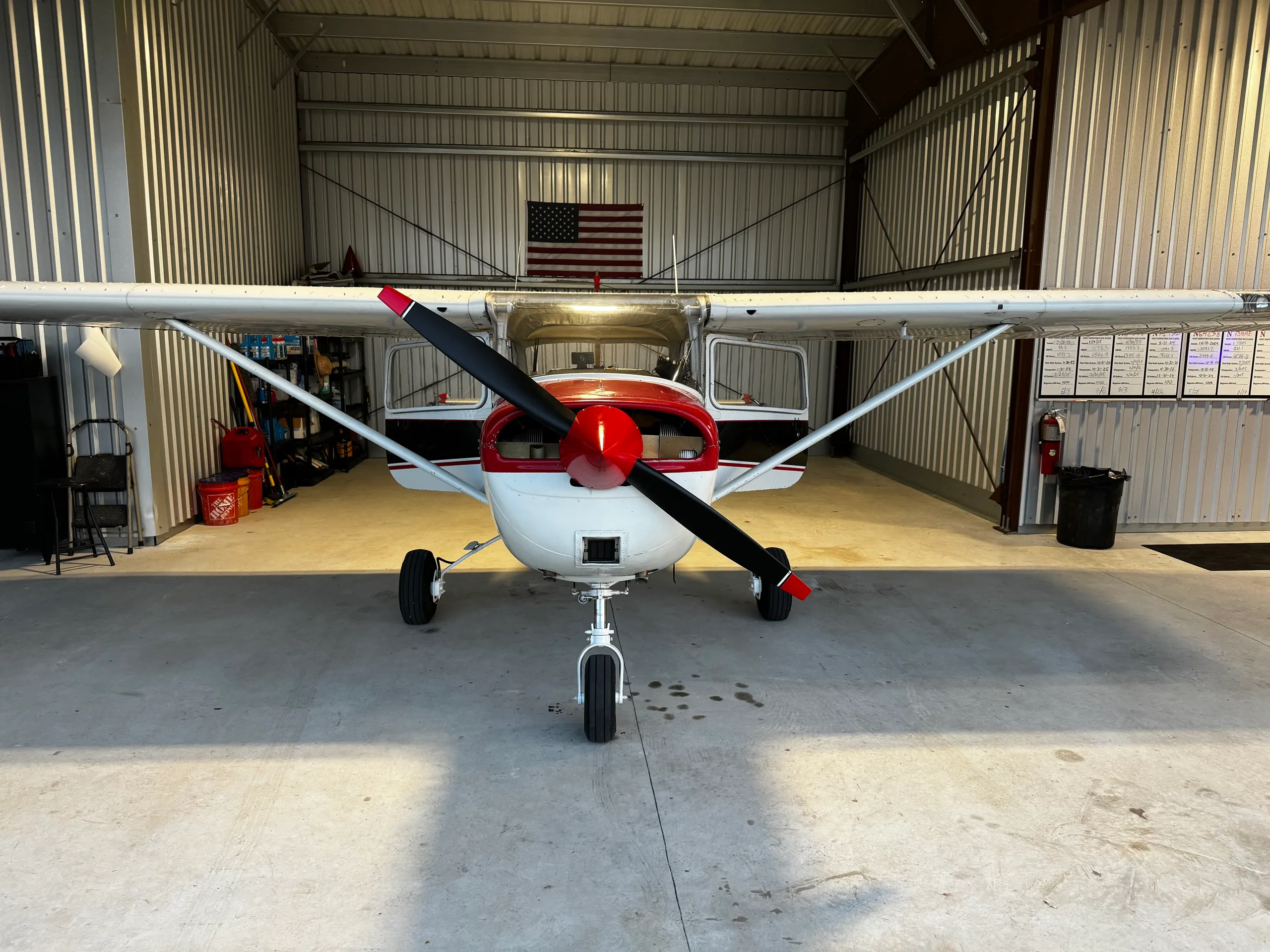 Front view of a white and red Cessna 172, N3640J, with a black stripe, parked in a hangar.