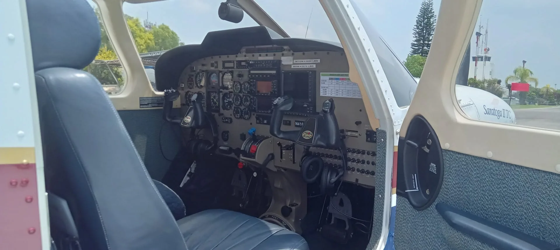 Side view of a small aircraft cockpit with instrument panel, yokes, and controls.