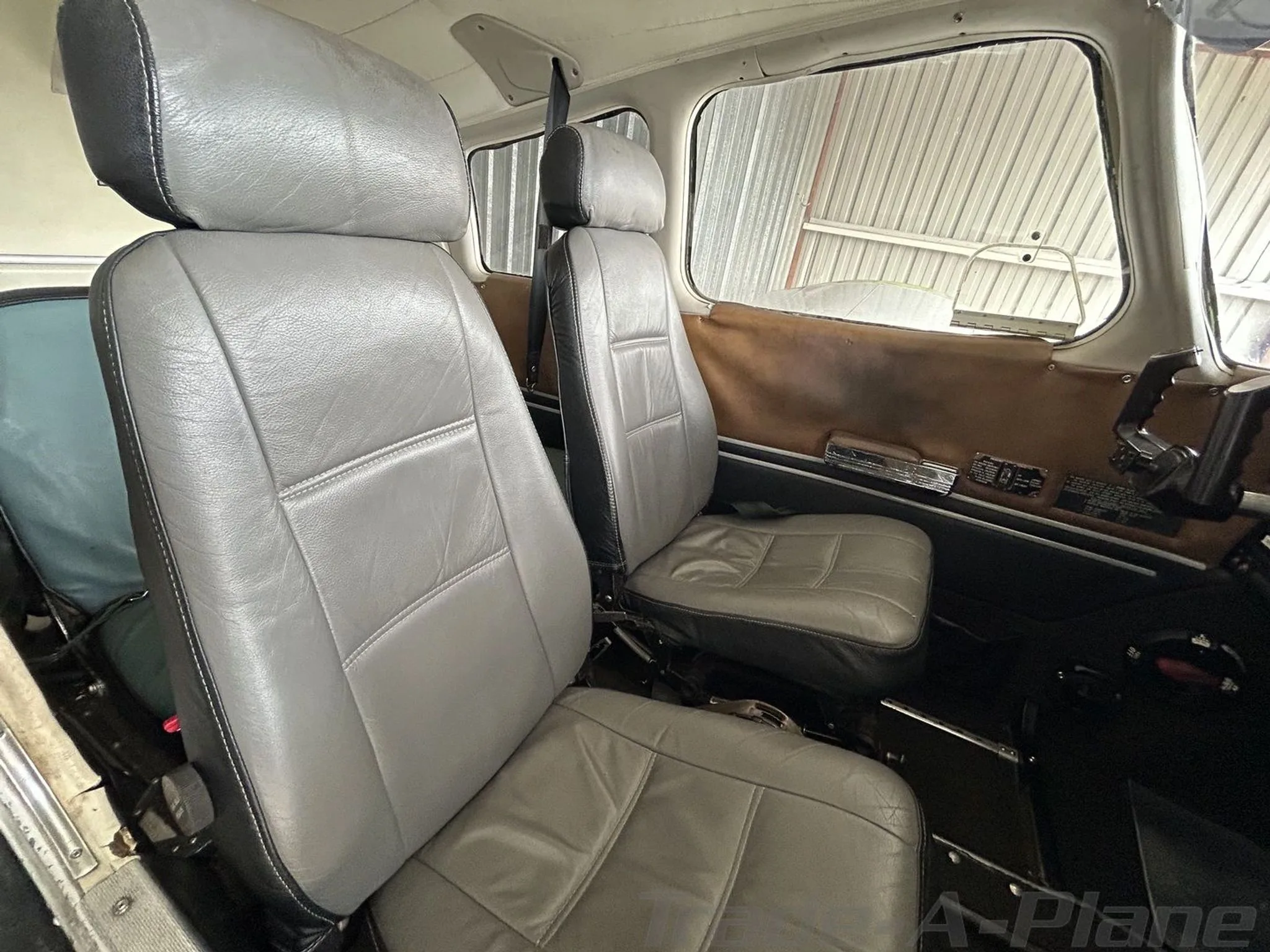 The gray leather front cabin seats of an aircraft, with brown side panels.
