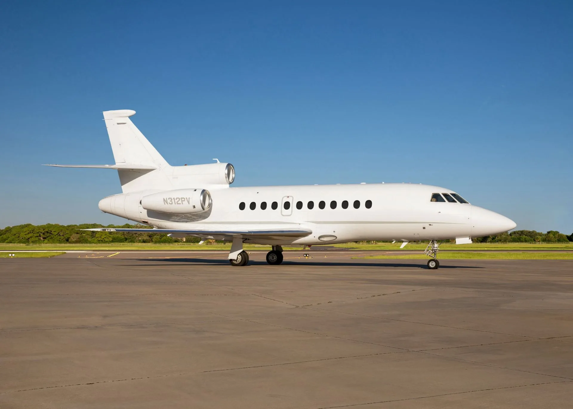 Dassault Falcon 900 on the tarmac with a white paint scheme.