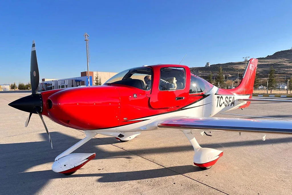 A close-up front-side view of a red and white single-engine aircraft (TC-SFA) parked on an airfield.