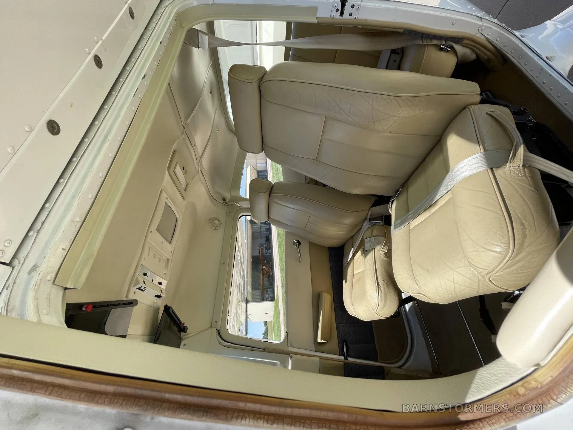 An overhead view of the light tan leather interior seats of a small aircraft cabin.