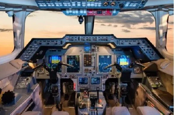 The cockpit of a modern business jet with multiple digital displays and controls, viewed from the pilot's seat.