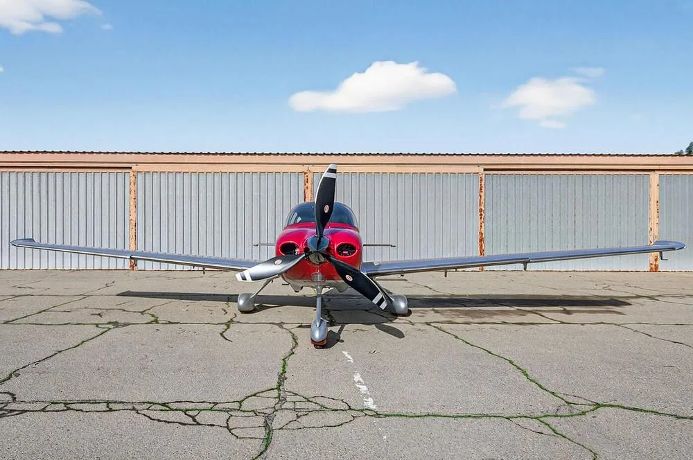 A head-on view of a red and silver single-engine aircraft, N512KP, parked on an airfield.