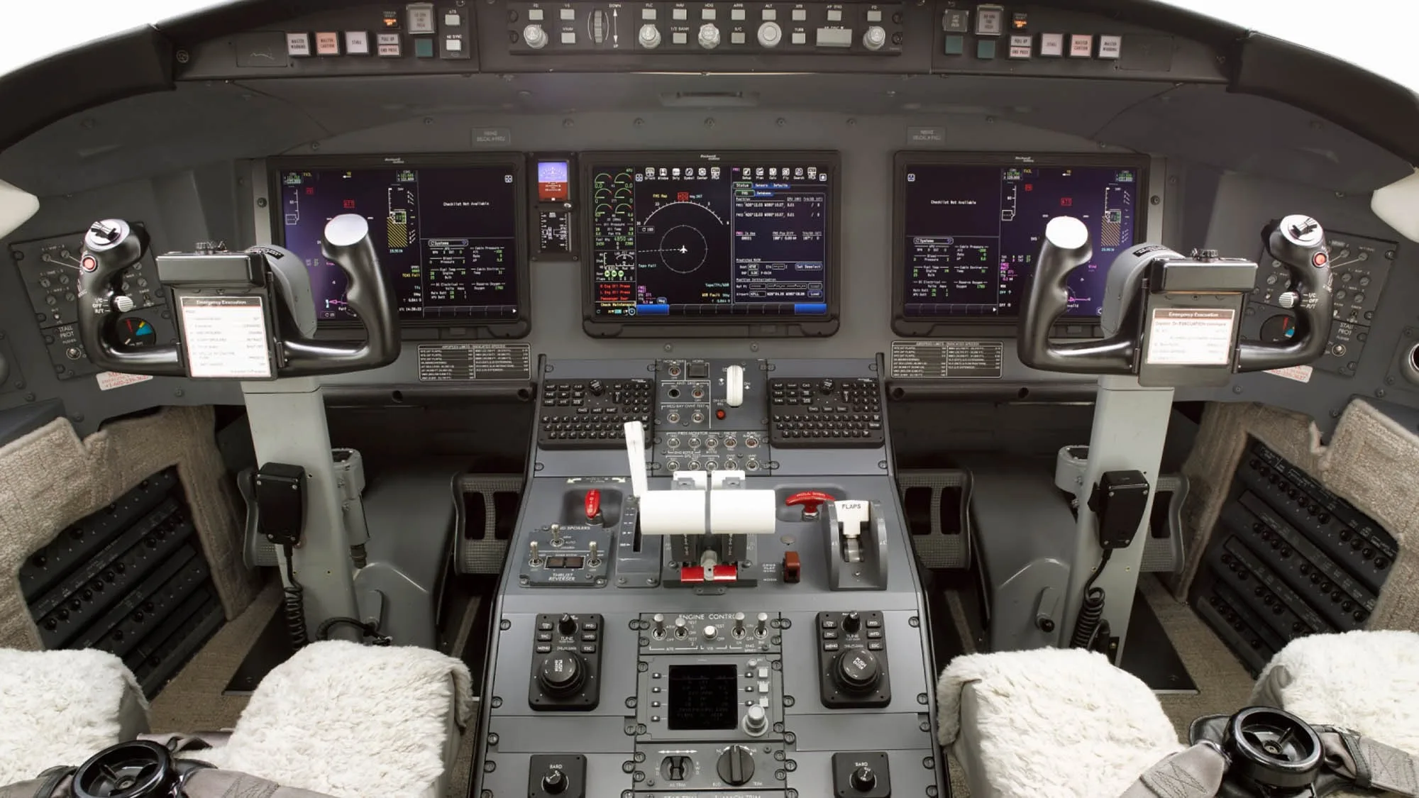 The cockpit of a Bombardier Challenger 604, showing the instrument panel with multiple display screens and control yokes.