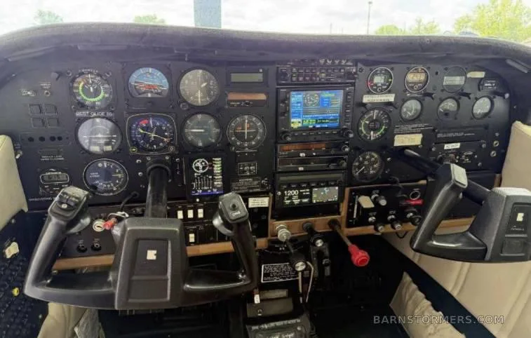 The cockpit instrument panel of a small aircraft, featuring analog gauges, two digital displays, and control yokes.