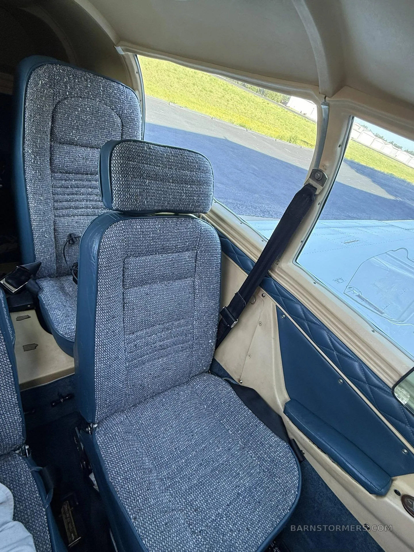 The interior cabin of a small aircraft with blue patterned fabric seats and blue side panels.