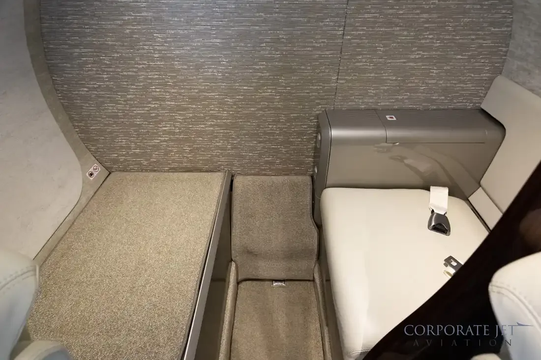 A close-up view of a light-colored seat and a storage compartment in the aircraft cabin.