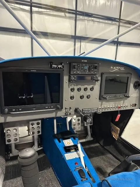 The cockpit of a Kitfox aircraft, showing the instrument panel with two large screens and blue interior accents.