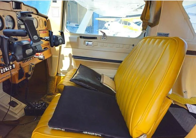 The cockpit and yellow passenger seat of a Cessna 150 aircraft.