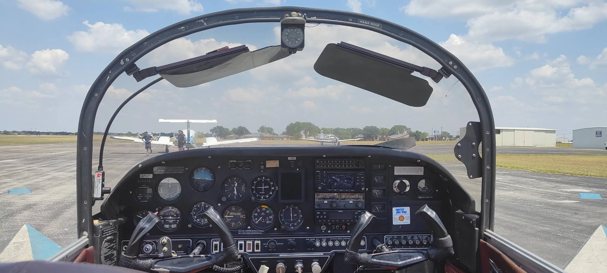 View from the cockpit of N74374, showing the instrument panel and the runway ahead with other aircraft.