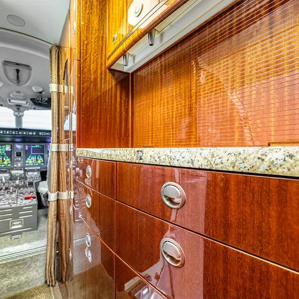A view of the aircraft galley with polished wood cabinetry and a granite countertop, looking towards the cockpit.