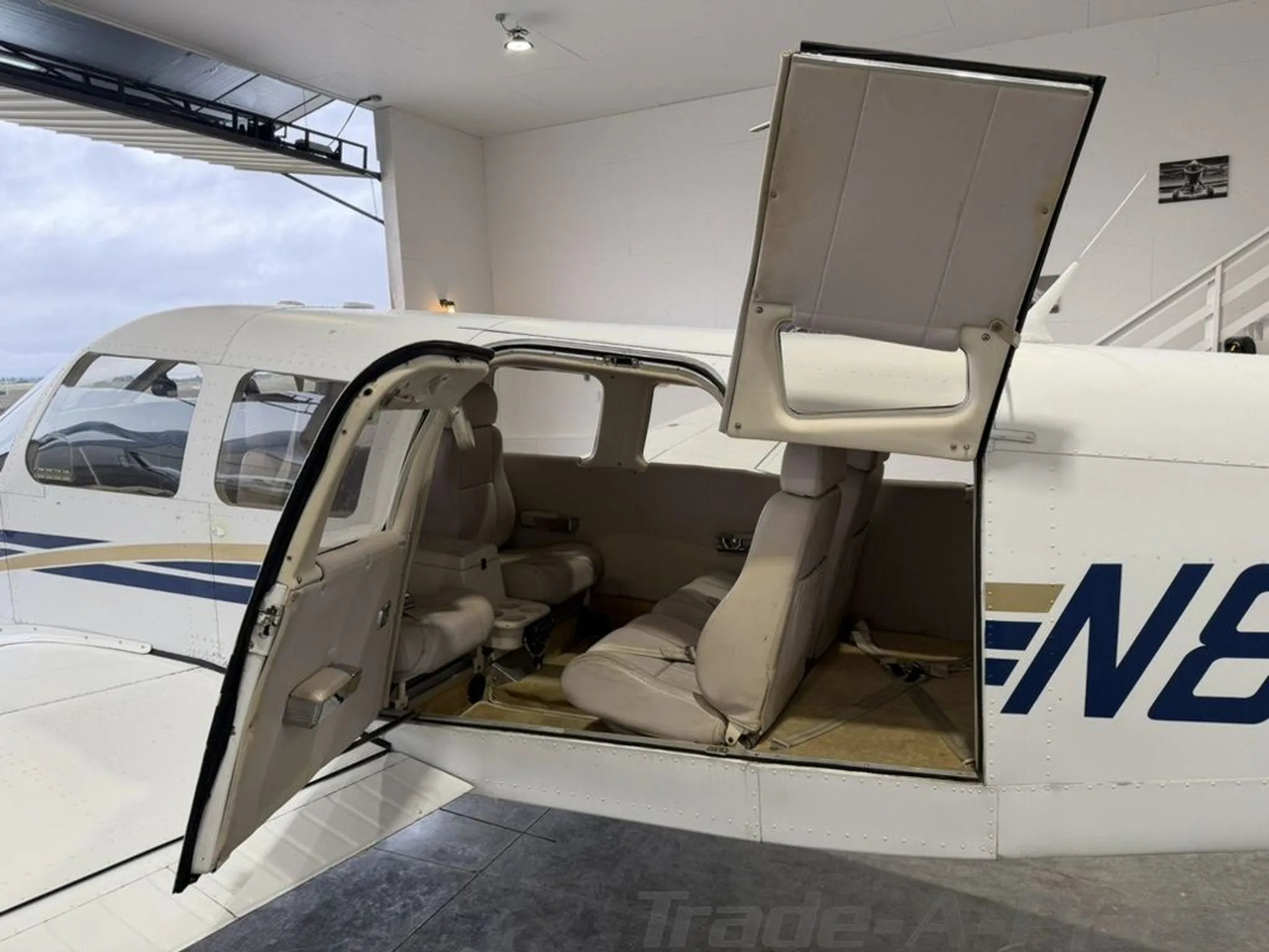 The light-colored interior cabin of a small aircraft with two rows of seats and open doors.