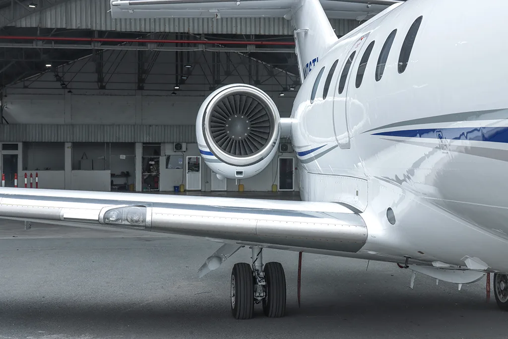 A close-up view of the wing, main landing gear, and rear-mounted engine of a white business jet.