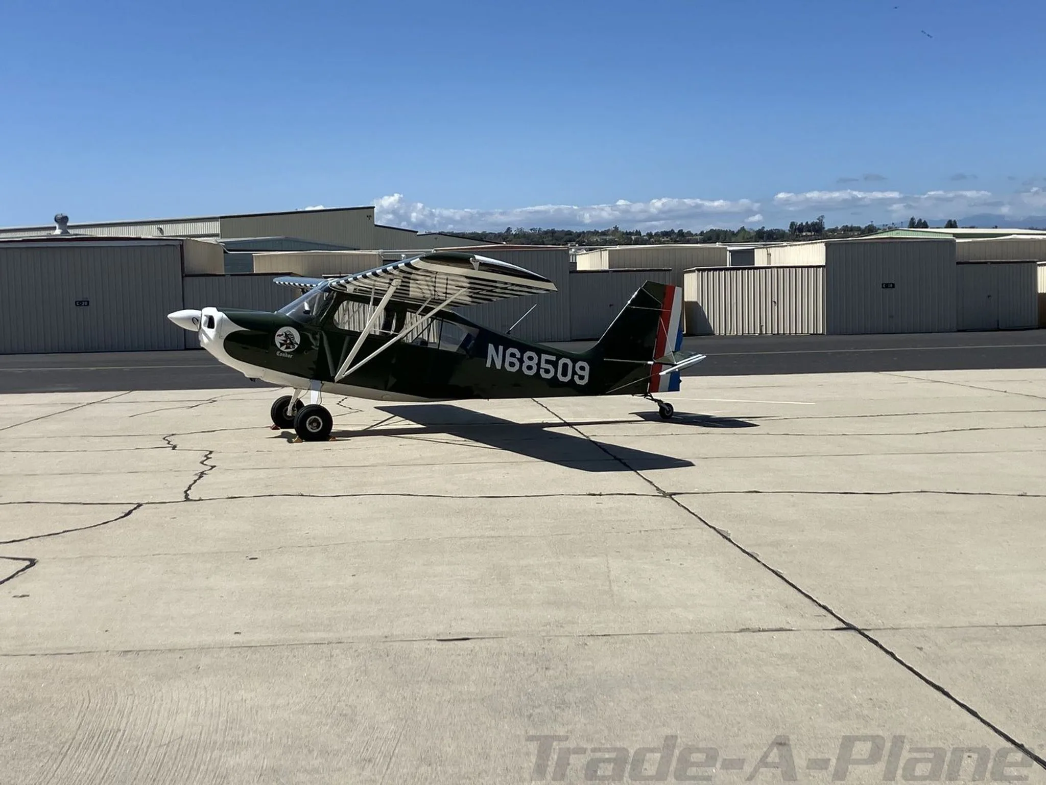 A side view of the green and white single-engine aircraft N68509 on an airport tarmac under a clear sky.