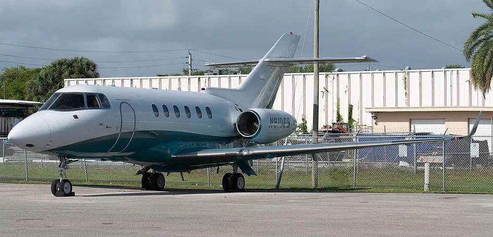 A Hawker 800XP business jet with a white and teal paint scheme parked on an airfield.