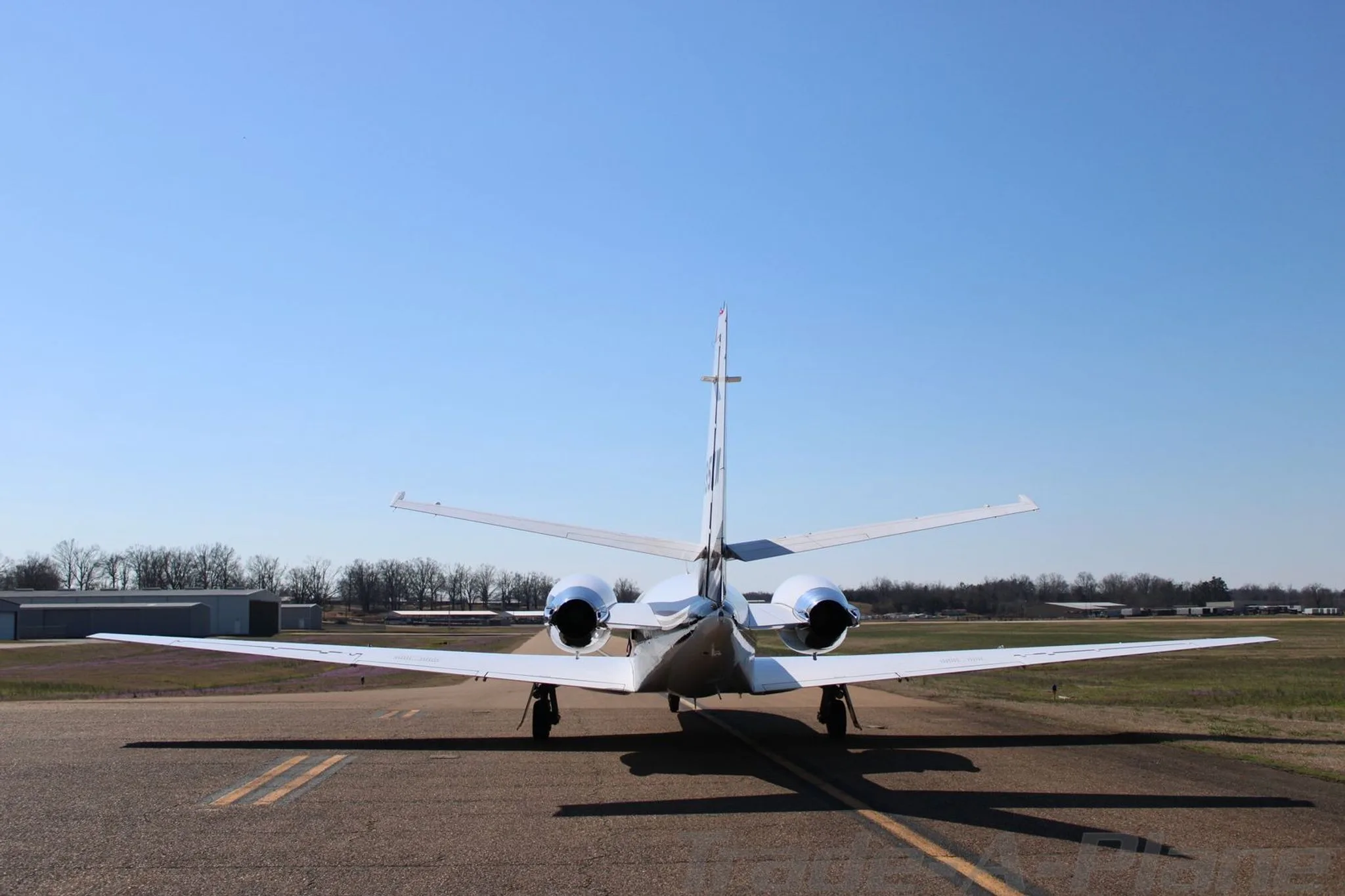 A rear view of a white Cessna Citation Encore business jet showing its twin engines and tail on the tarmac.