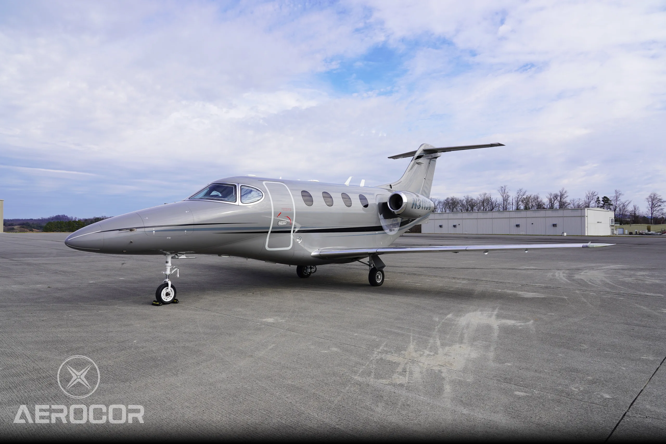 A gray Raytheon Premier I business jet, registration N311SQ, parked on a tarmac under a cloudy sky.