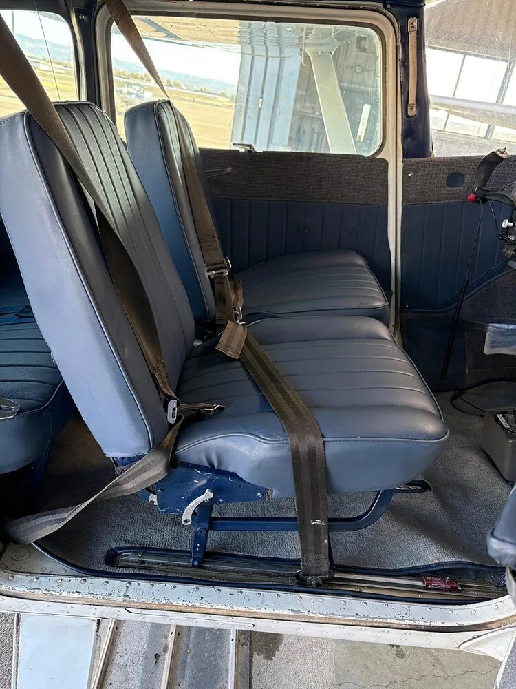 The blue upholstered passenger seats with seatbelts inside a small aircraft cabin, viewed from the front.