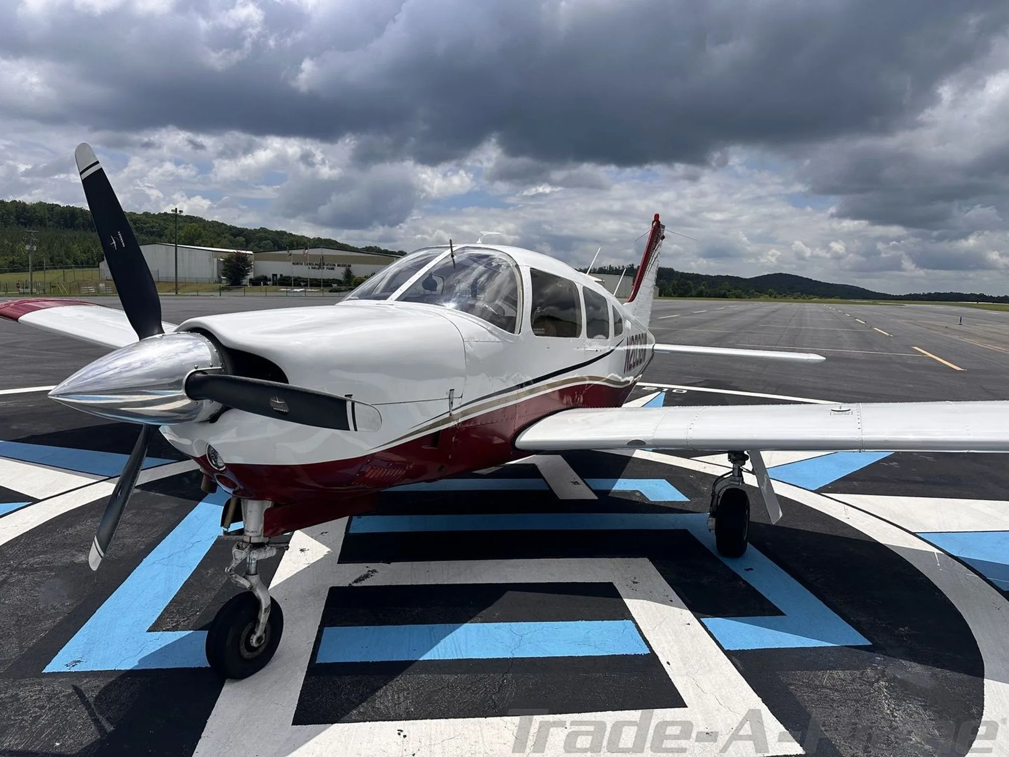 A front-side view of the white and red aircraft N203BW, showing its propeller and landing gear.