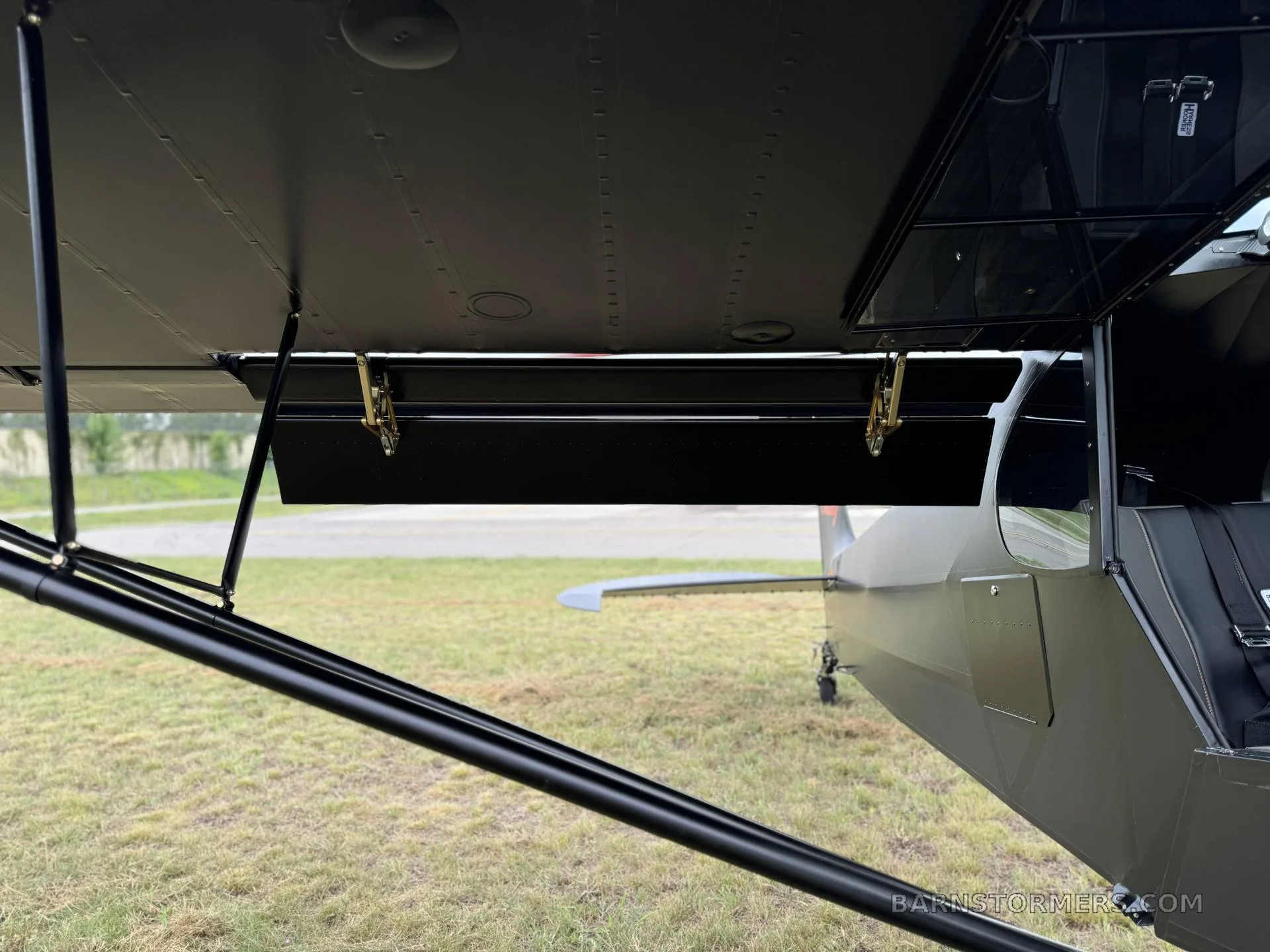 A close-up view of the black Super Cub's wing underside and fuselage, showing a small storage compartment.