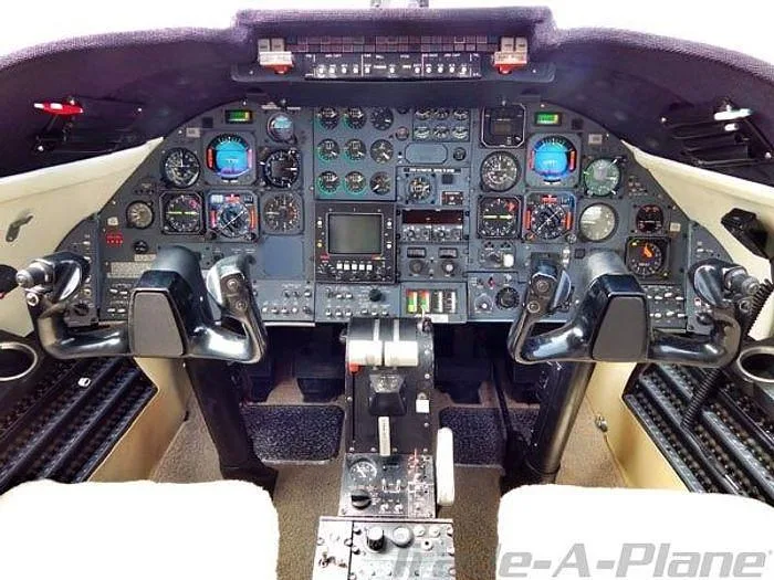 The cockpit features a complex instrument panel with analog gauges, digital displays, and dual control yokes.
