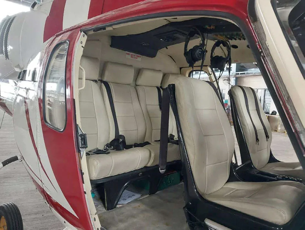 The open door of the helicopter revealing the light beige interior seats and part of the red and white exterior.